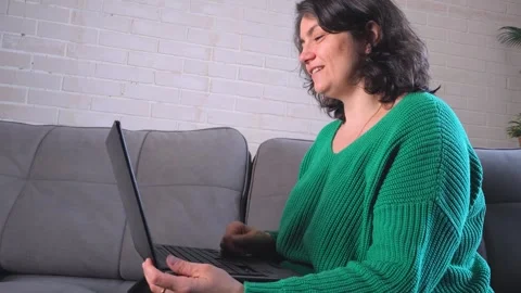 Woman sitting on couch using laptop at home in a relaxed setting Stock Footage 340462855