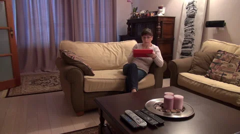 Woman sitting on a couch, working with tablet computer at home Stock Footage 33796954