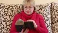 Woman sitting on a divan and reading old book HD Footage