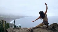 A Woman Sitting On The Edge Of A Cliff In A Pose War Overlooking The Ocean Raise Stock Footage