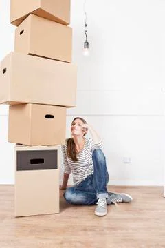 Woman sitting on floor besides stack of cardboard boxes Stock Photos