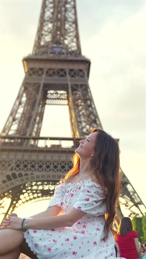 Woman sitting in front of Eiffel Tower at sunset in Paris Stock Footage 313796902