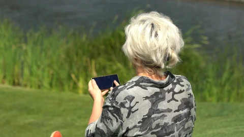 Woman sitting on grass using a mobile phone Stock Footage 94459033
