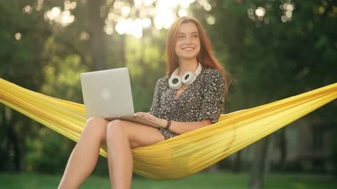 A woman sitting in a hammock on nature and a laptop in her hands, working Stock Footage 157923053