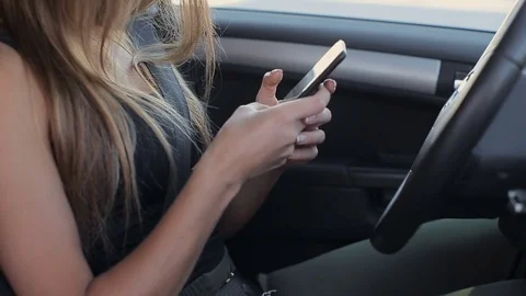 Woman sitting in her own car, contacting with someone through her smartphone Stock Footage