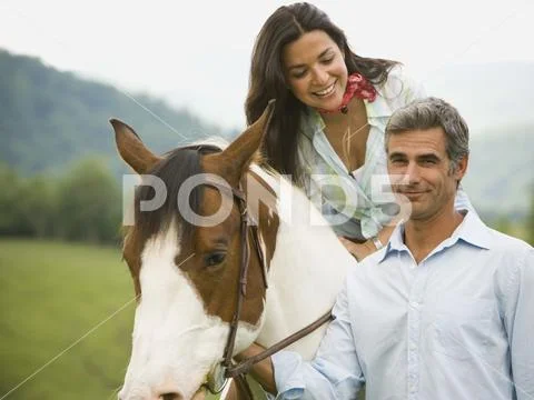 Woman sitting on a horse with a man beside her Stock Photos