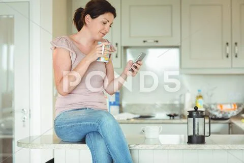 Woman Sitting On The Kitchen Counter At Home