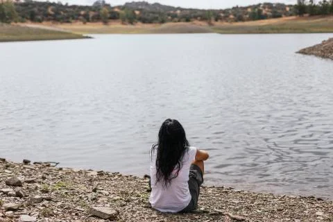 Woman sitting on the lake shore Stock Photos