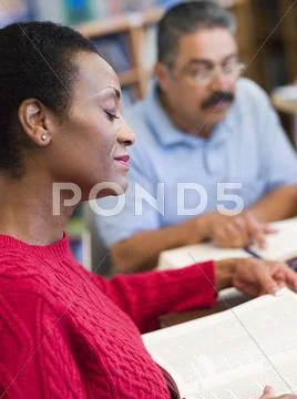 Woman sitting near man in library with books and notepads (selective focus) Stock Photos