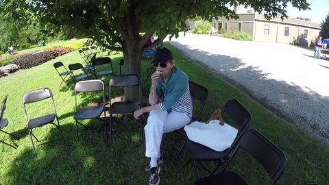 A woman sitting on an outdoor bench, snacking Stock-Footage 78251553