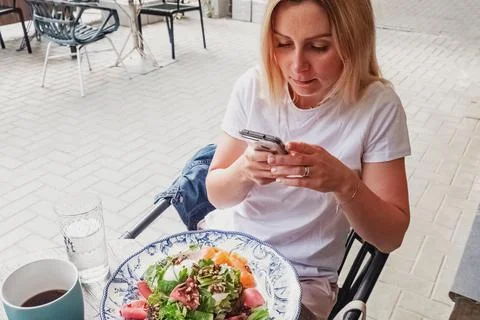 Woman sitting outside in cafe using her smartphone Stock Photos