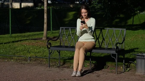 Woman sitting in park using smartphone Stock Footage 91901552