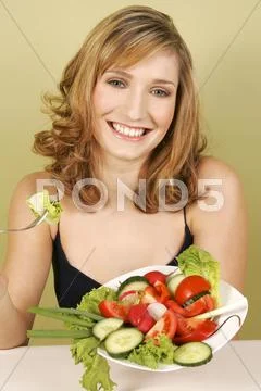 A woman sitting with a plate of salad. Stock Photos