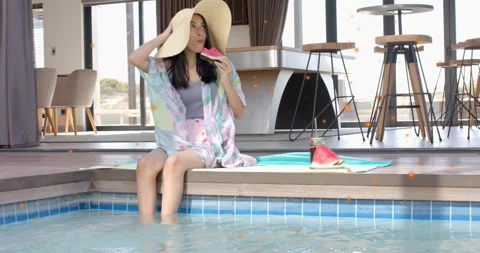 Woman sitting pool edge picking up watermelon slice, taking bites, adjusting hat Stock Footage 330463374