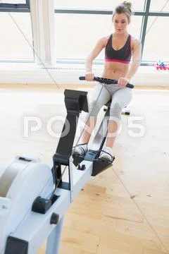 Woman sitting at the row machine pulling Stock Photos