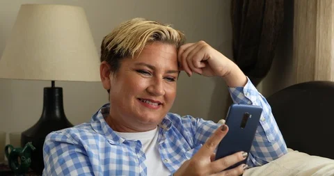Woman sitting on sofa and using smart phone at home 2 Stock-Footage 117737498