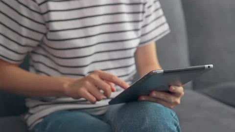 Woman sitting on the sofa and using digital tablet online social. 스톡 동영상 153964083