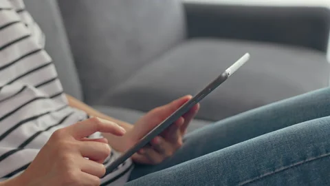Woman sitting on the sofa and using digital tablet online social. 스톡 동영상 153970069