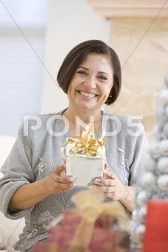 Woman Sitting On Sofa Holding A Christmas Gift Stock Photos