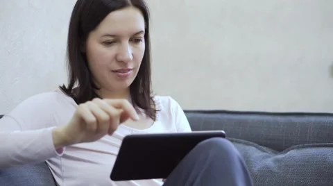 Woman sitting on sofa with tablet pc Stock Footage 68736087