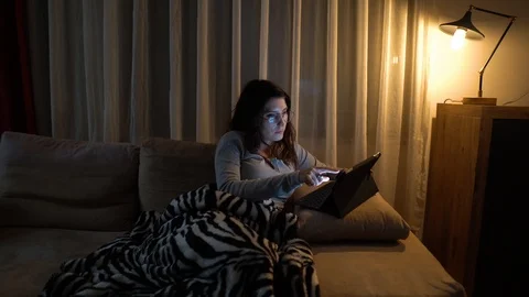 Woman sitting on sofa using her tablet surfing on internet Stock Footage 121564719