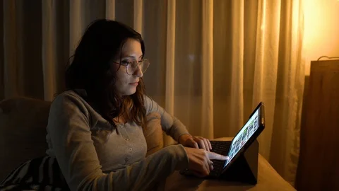 Woman sitting on sofa using her tablet surfing on internet Stock Footage 121564836