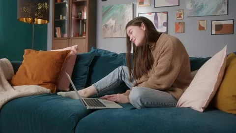 Woman is sitting on the sofa, using laptop. She is calling on computer for Stock Footage 149674792