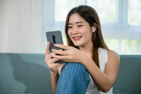 Woman sitting on sofa using mobile smart phone at living room Stock Photos