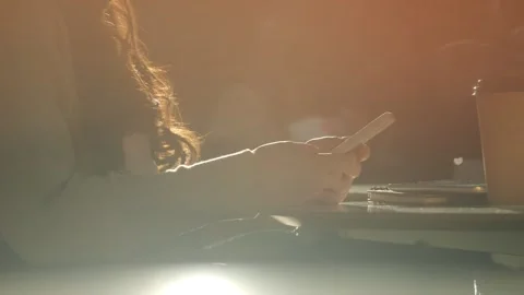 Woman is sitting at a table with a cell phone in her hand Stock Footage 303052953