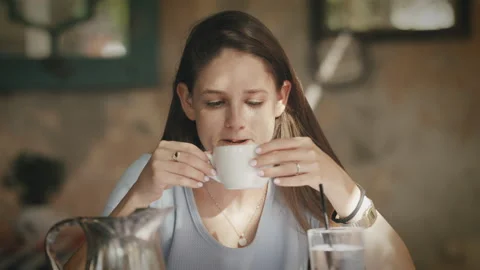 Woman sitting at table drinking coffee in cafe Stock Footage 275696765