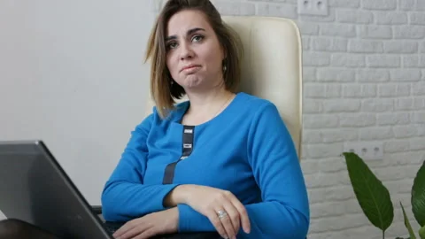 Woman sitting at the table in the office, medium shot. The girl empathizes, her Stock Footage 87232986