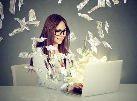 Woman sitting at table using working on a laptop computer making money Stock Photos