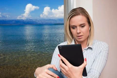 Woman sitting on a window using tablet Stock Photos