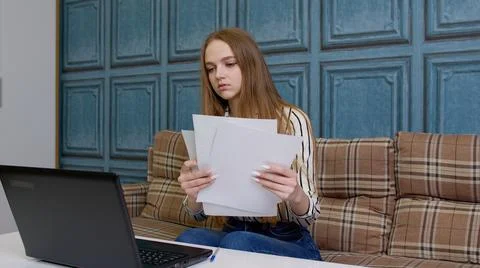 Woman sittingat home looking at documents analyzes data checks papers working on Stock Photos