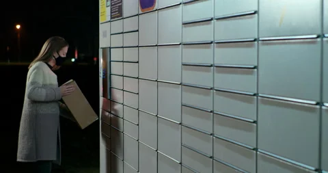 Woman Skans Bar Code in Parcel Locker to Send, Return or Deliver Box at Night Stock Footage 144076276