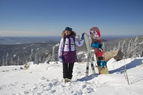 A woman in ski equipment is standing on the top of a mountain. A girl at a sk Stock Photos