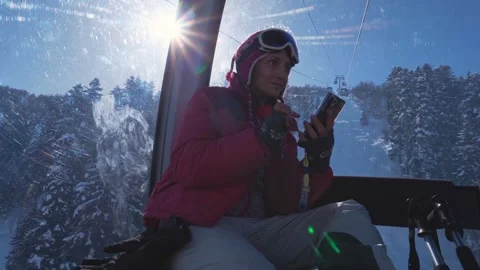 Woman skier in cable car using smartphone check smart ski resort app for re.. Vídeos de archivo 342130688