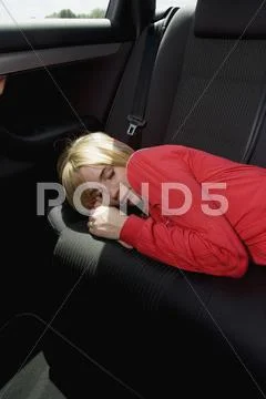 A woman sleeping on the back seat of a car Stock Photos