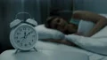 Woman sleeping in bed with alarm clock showing midnight time, night dreams 4k or 4k+ Resolution