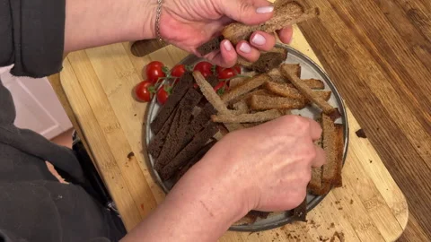 A woman slices rye gray bread on a wooden countertop in the kitchen 스톡 동영상 301245488