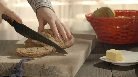 Woman slicing fresh bread with a sharp knife Stock Footage 147143863