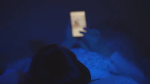 A woman with a smartphone in bed, a beautiful woman suffering from insomnia and Stock Footage