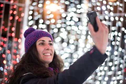 Woman with smartphone land christmas lights sending message Stock Photos