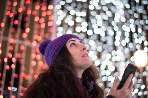 Woman with smartphone looking christmas lights Stock Photos