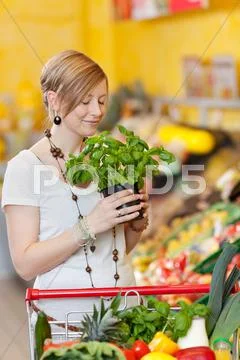 Woman smelling fresh basil in a supermarket Stock Photos