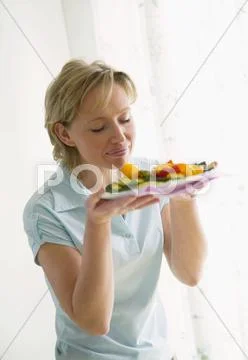 Woman smelling grilled vegetables on plate Stock Photos