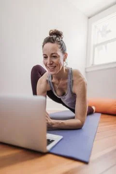 Woman smiles while using computer to practice yoga in her home Foto stock