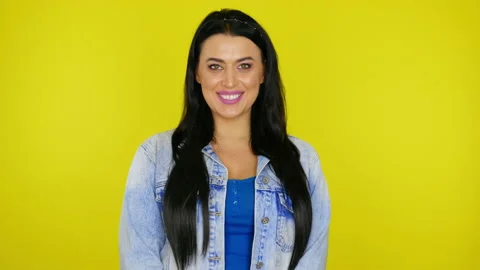 Woman smiling and posing while looking at the camera on a yellow background Stock Footage 130488176
