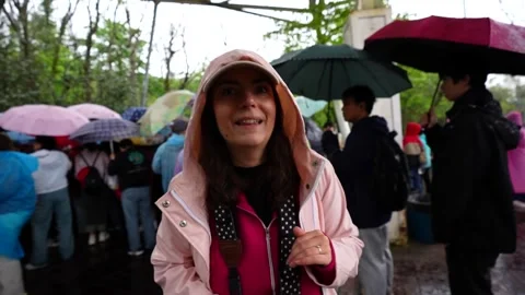 Woman smiling and queuing with a crowd in the rain Stock Footage 334941476