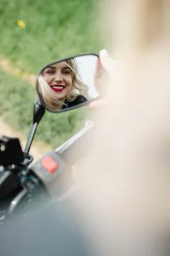 A woman is smiling at the camera while riding a motorcycle Stock Photos